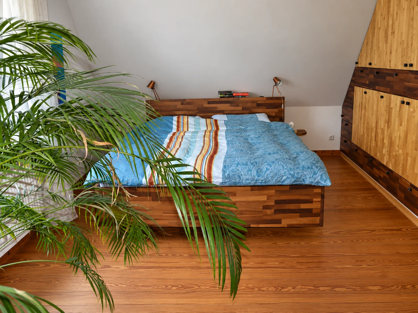 Maßgefertigtes Holzbett mit passendem Einbauschrank unter einer Dachschräge